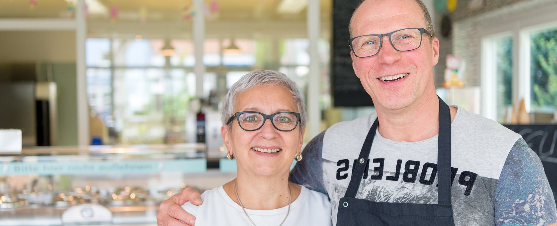 Ein Ehepaar, im Hintergrund der raum einer Eisdiele.