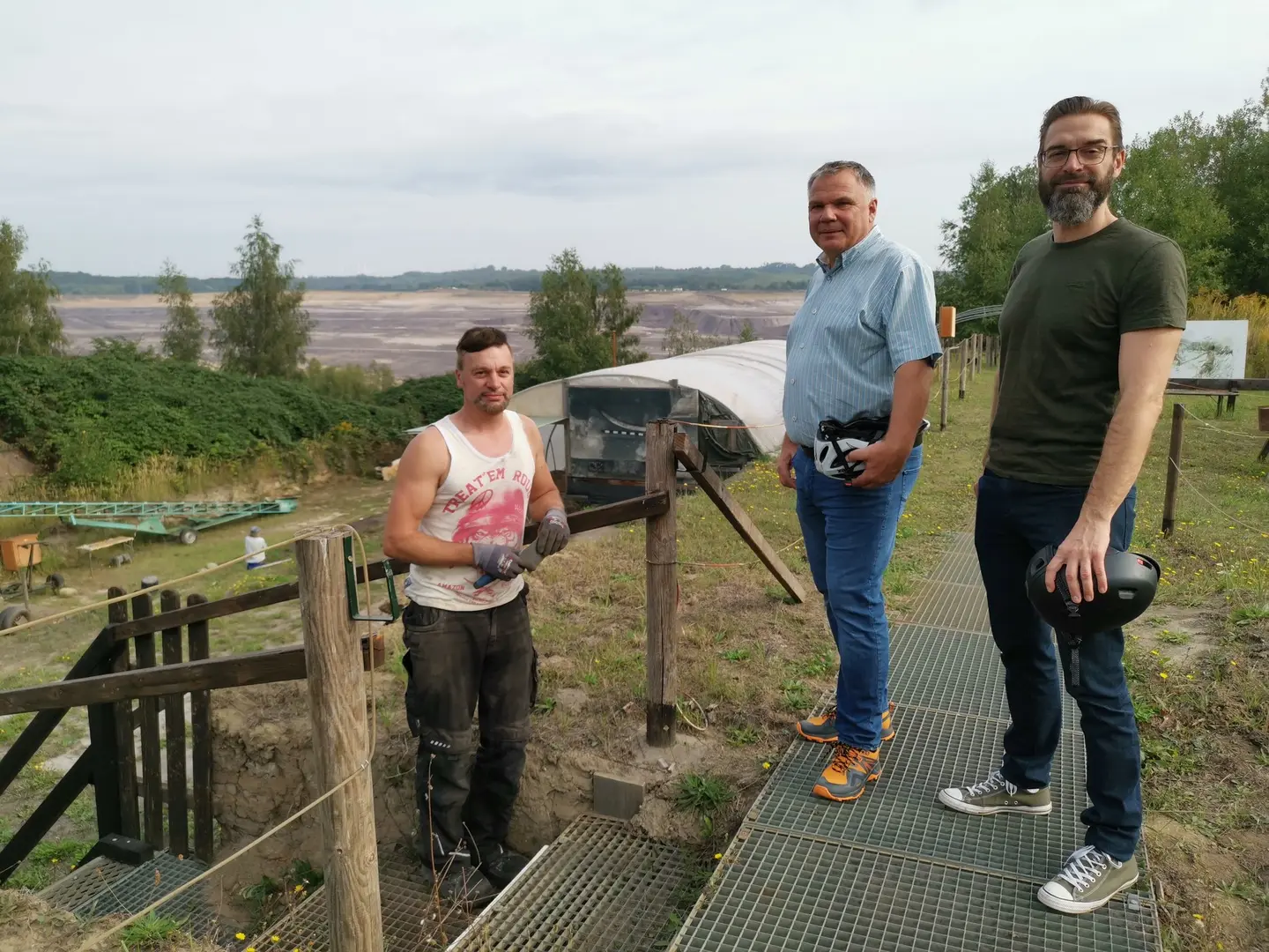 Drei Männer stehen am Tagebau.