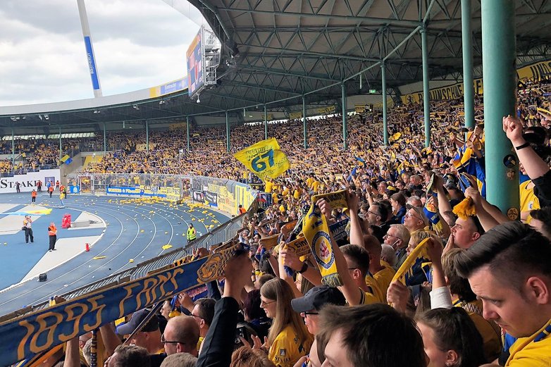 Hunderte Fußballfans stehen auf einer Tribüne.