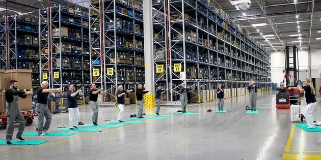 Menschen in einer Lagerhalle machen Mobilitätsübungen.