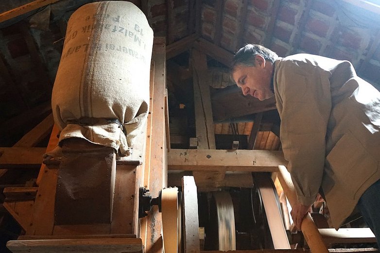 Ein Mann schaut zu, wie Korn gemahlen wird.