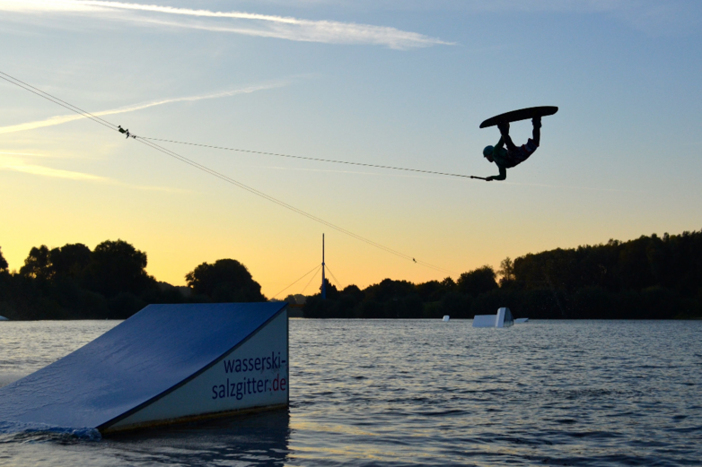 Ein Wakeboarder springt über eine Rampe im Salzgittersee.