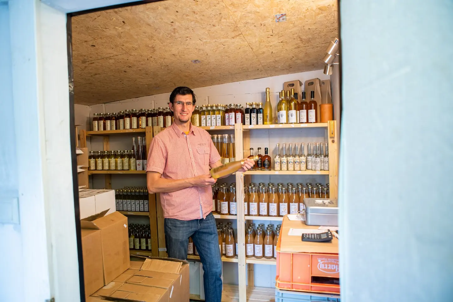 Ein Mann steht vor einem Flaschenregal.