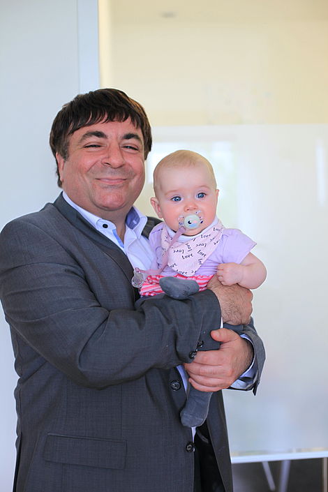 Geschäftsführer Anhal Osman mit einem Mitarbeiterbaby auf dem Arm
