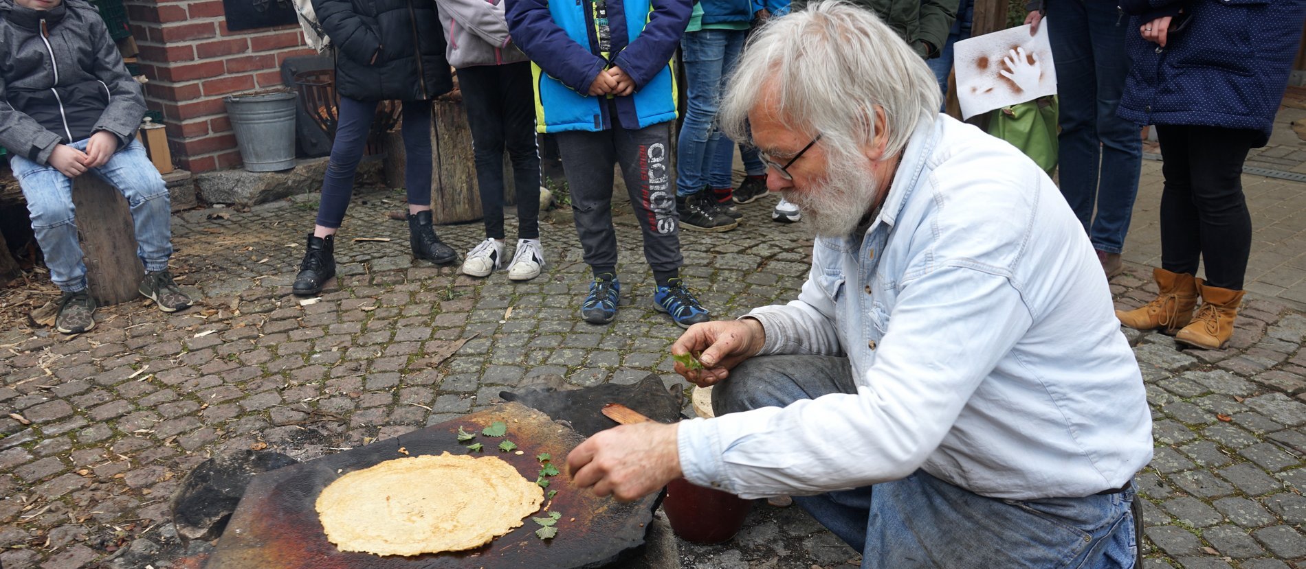 Jean-Loup Ringot legt Brennnesselblätter auf den heißen Stein.