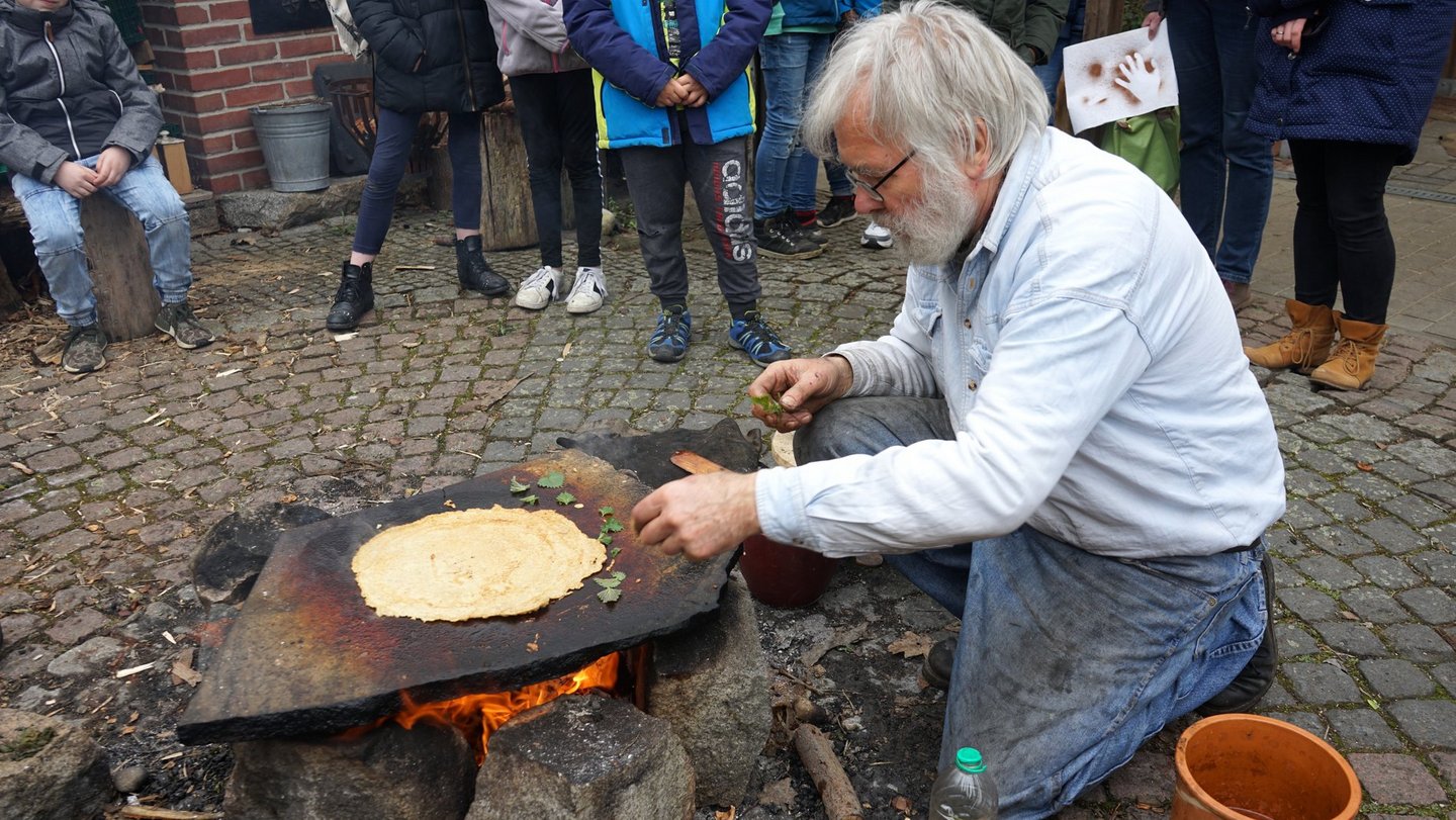Jean-Loup Ringot legt Brennnesselblätter auf den heißen Stein.