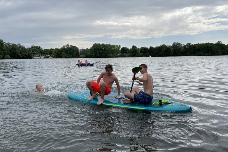 Zwei Jungs sitzen auf einem SUP-Board.
