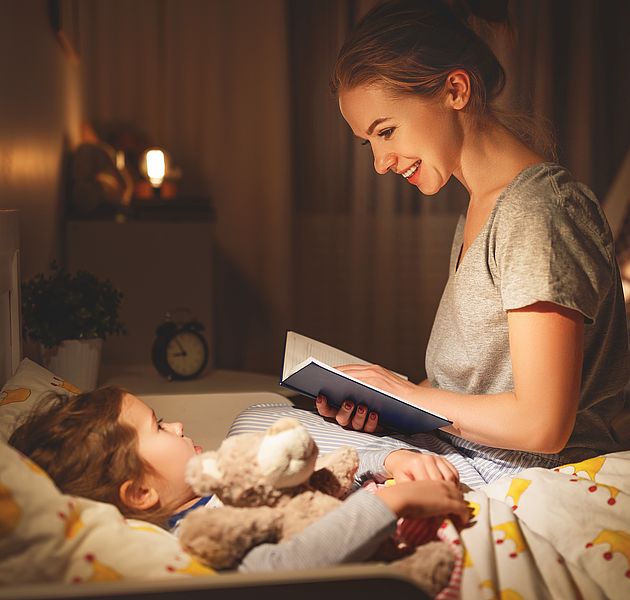 Eine Mutter liest ihrem Kind vor, welches schon im Bett liegt. (Bildrechte: shutterstock)