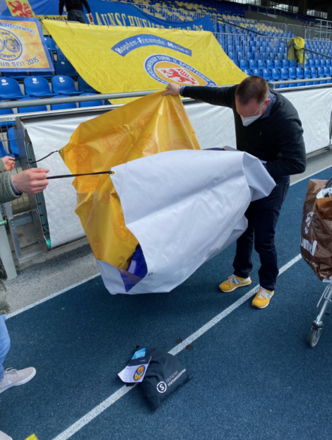 Ein Mann faltet eine Fanclub-Fahne auf.