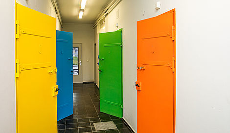 Ein Gang mit vier verschiedenfarbigen Türen. 