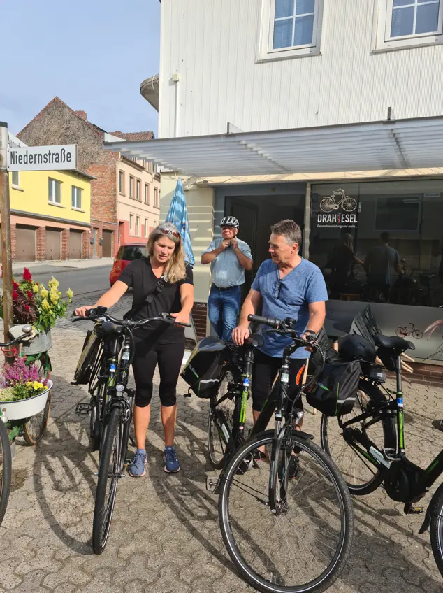 Drei Leute stehen vor mehreren Fahrrädern.
