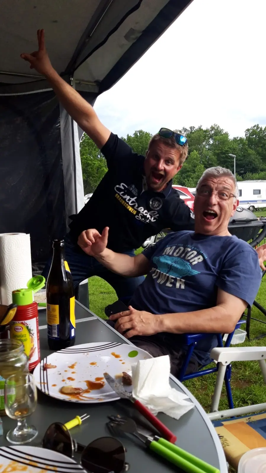 Zwei jubelnde Männer auf einem Campingplatz