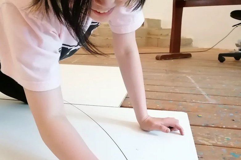 Eine Frau malt auf einem Bogen Papier auf dem Boden.