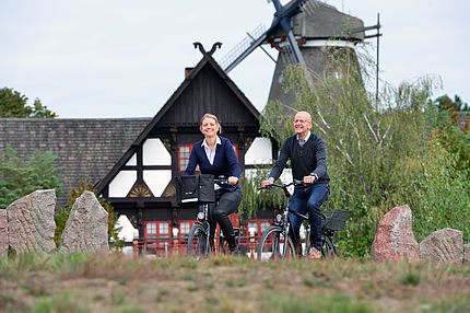Ein Radfahrer und eine Radfahrerin fahren Rad vor einem historischen Fachwerkgebäude.