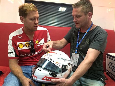 Sebastian Vettel und Jens Munser besprechen den Formel-1-Helm.
