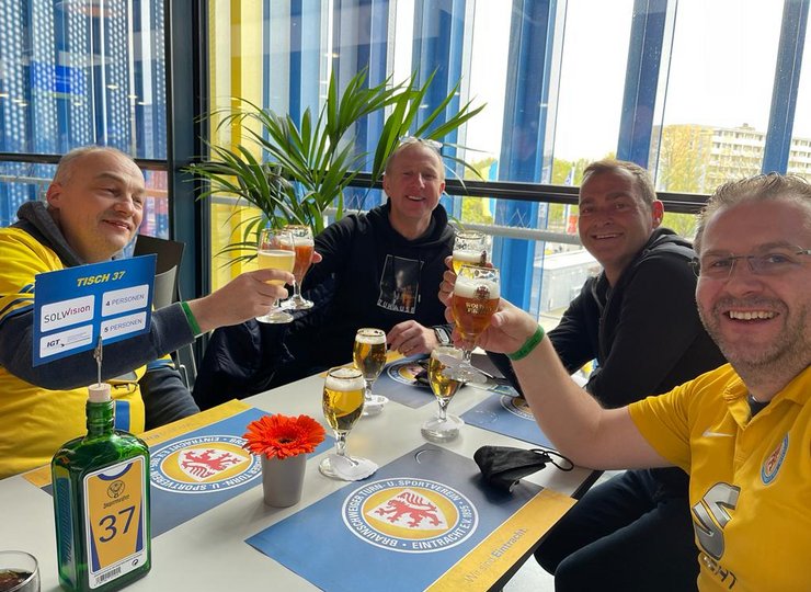 Vier Männer sitzen an einem Tisch und Trinken beherzt Bier.