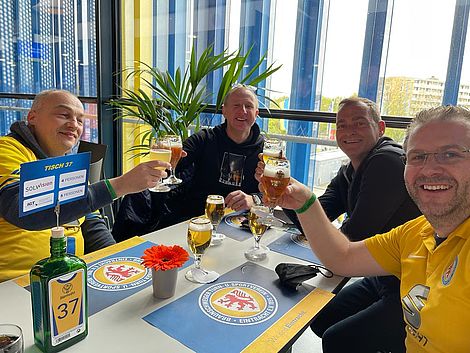 Vier Männer sitzen an einem Tisch und Trinken beherzt Bier.