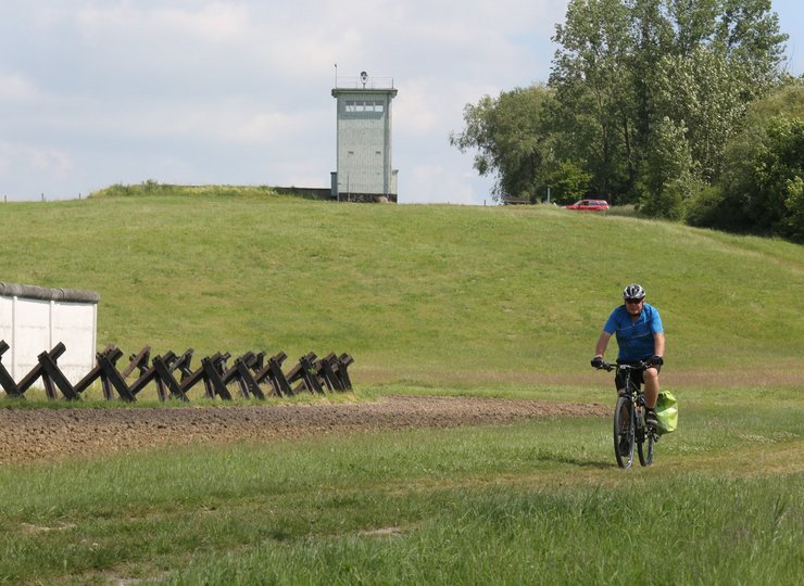 Ein Fahrradfahrer fährt an einem übriggebliebenen Abschnitt der ehemaligen innerdeutschen Grenze vorbei.