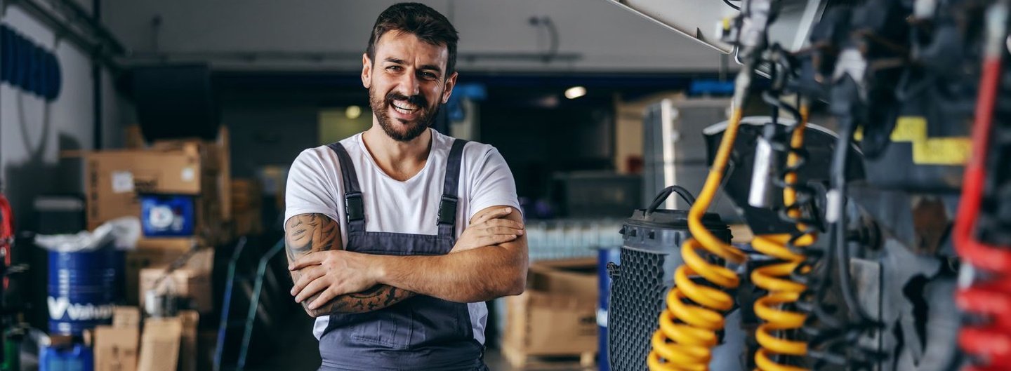 Ein Mann steht in einer Werkstatt und lächelt.