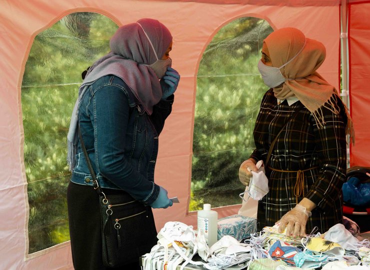 Zwei Muslima mit Kopftuch und Mundschutz unterhalten sich.