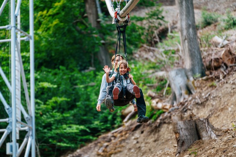 Mutter und Kind sitzen im Gurt der Baumschwebebahn Bad Harzburg.
