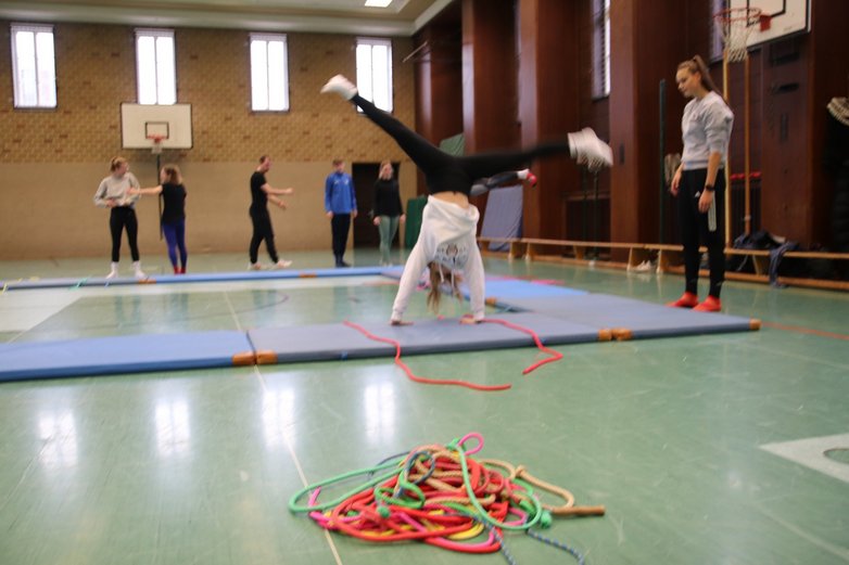 Eine junge Frau schlägt ein Rad in der Sporthalle.