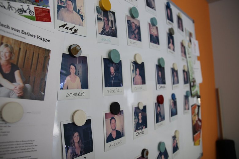 Eine Magnettafel mit Portraitfotos. 