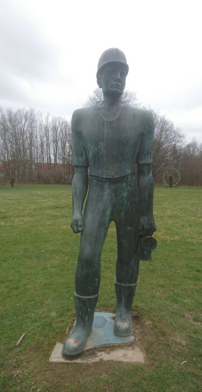 Man blickt auf eine lebensgroße Bronzestatue eines Bergmannes.