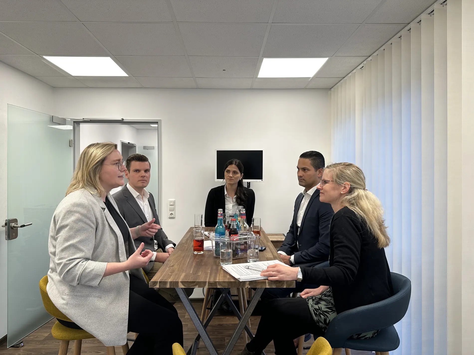 Fünf Personen sitzen um einen Tisch und unterhalten sich. 