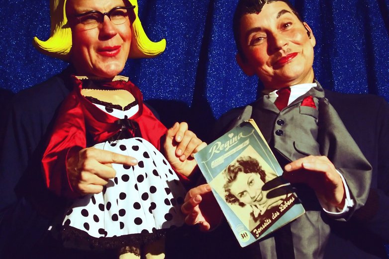 Zwei Puppen auf einer Kleinkunstbühne.