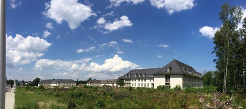 Ehemalige Kasernengebäude unter einem strahlend blauen Himmel.