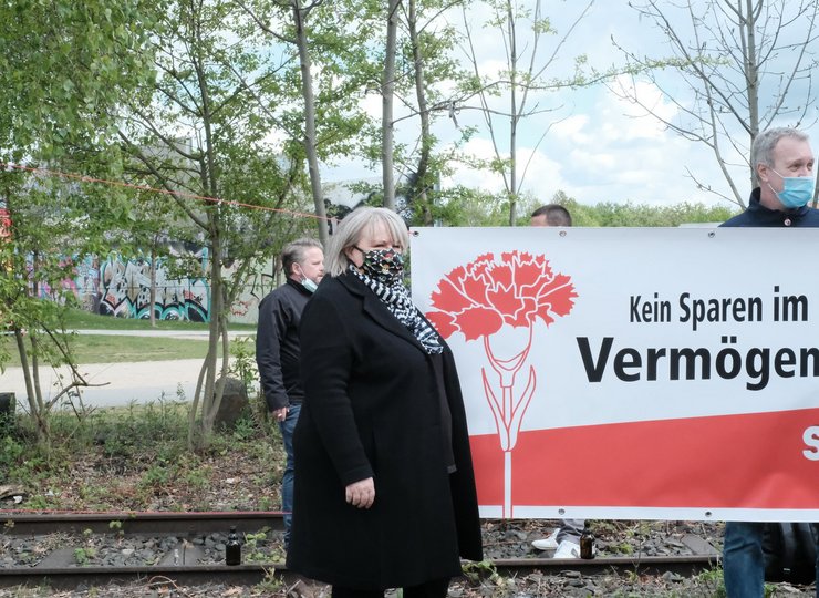 Eine Gewerkschaftlerin steht links neben einem Plakat.
