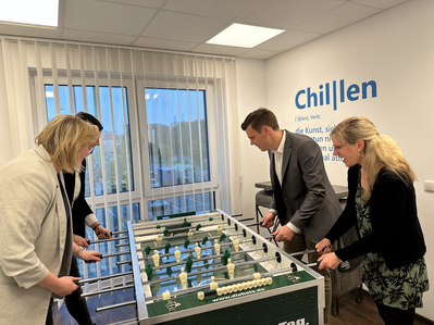 Vier Personen spielen an einem Kicker. 