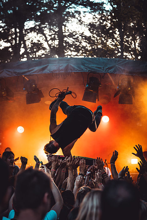 Ein Mann springt von einer Bühne kopfüber in die Zuschauermenge.