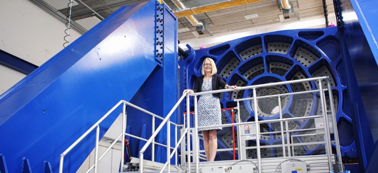 Eine Wissenschaftlerin steht vor einer gewaltigen Machine.