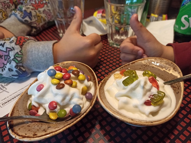 Zwei Kinder am Tisch vor ihren Eisportionen.