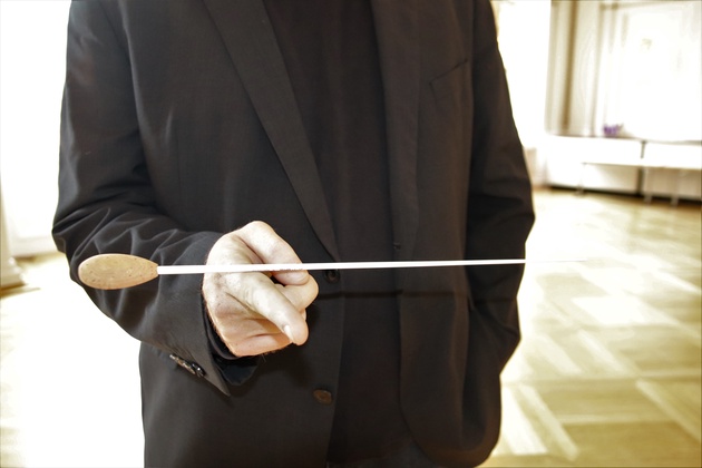 Ein Mann balanciert einen Taktstock auf der Hand.