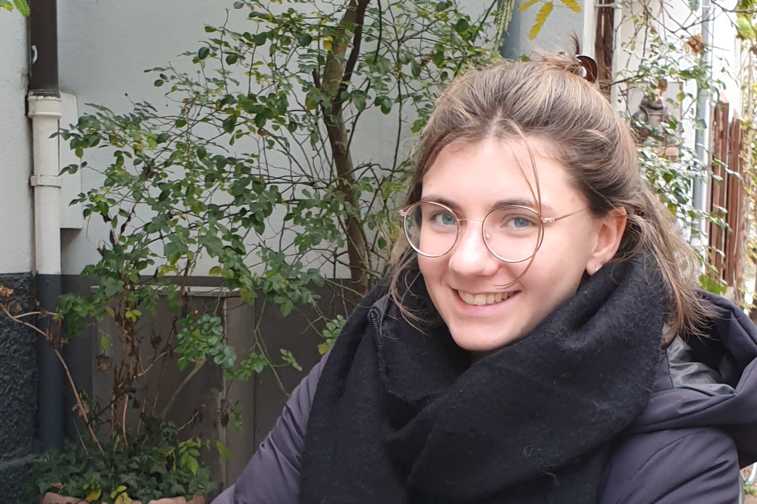 Eine junge Frau mit Brille schaut in die Kamera.