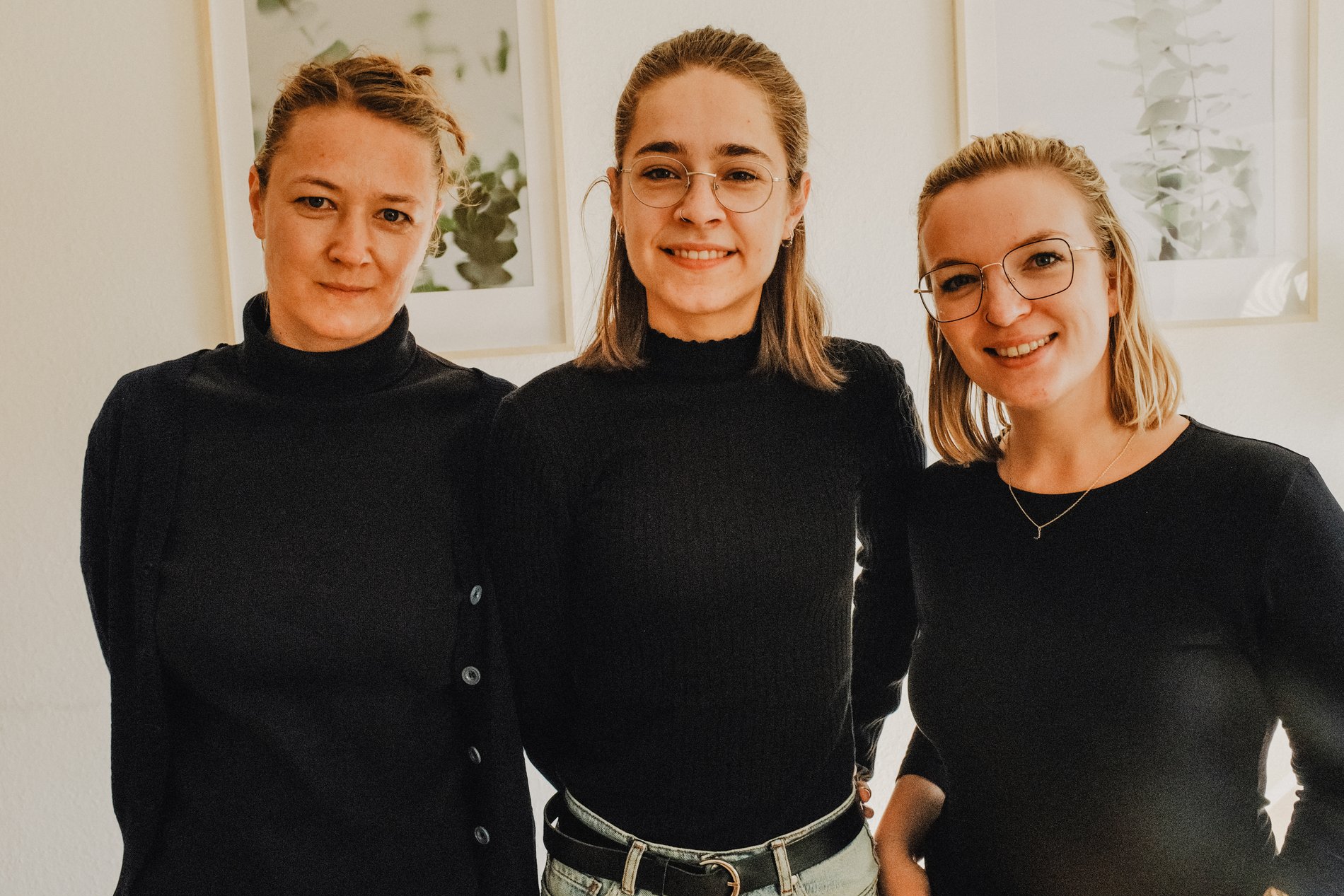 Drei junge blonde Frauen in schwarzer Kleidung.