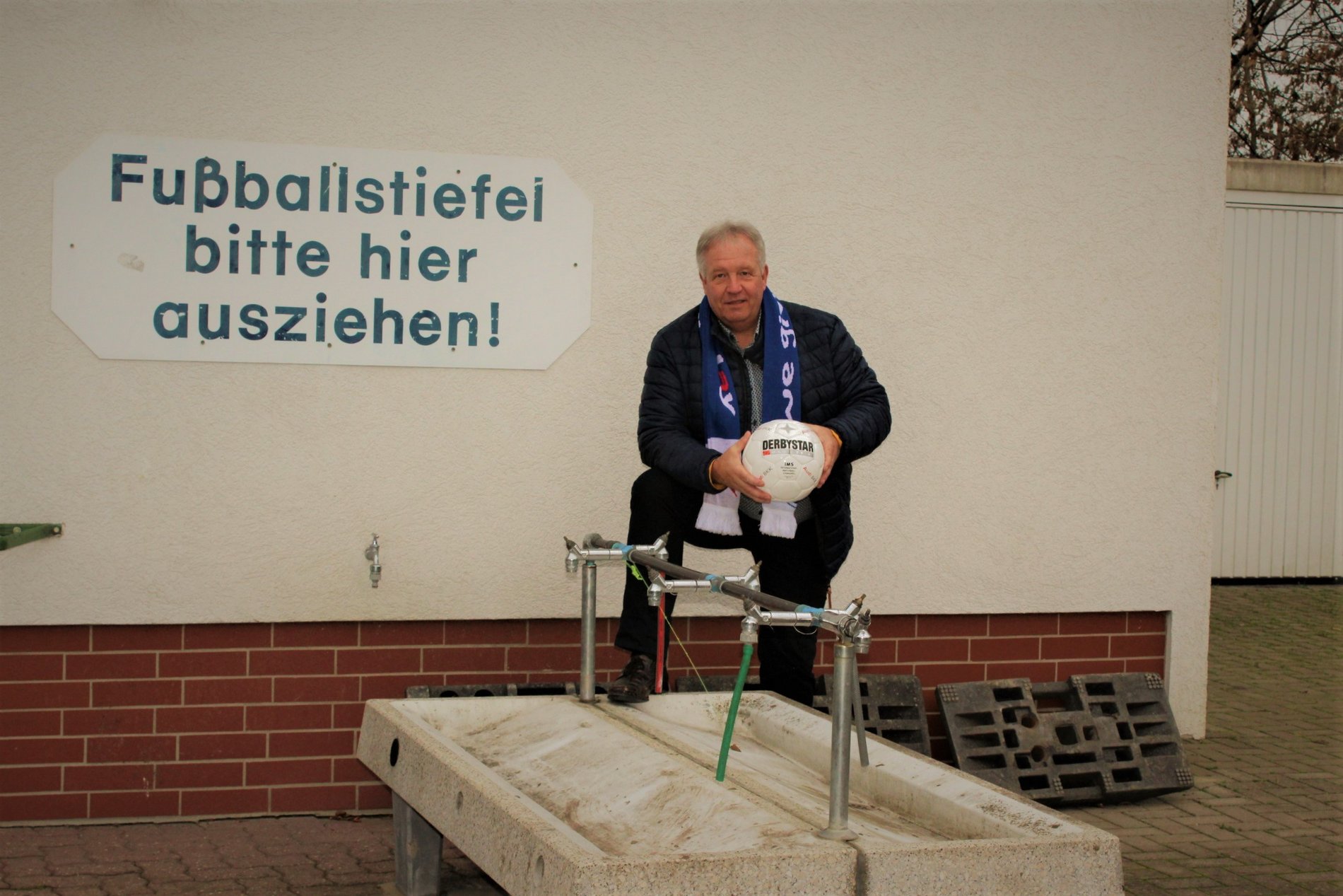 Ein Mann an einer Wasch-Station für Fußballschuhe.