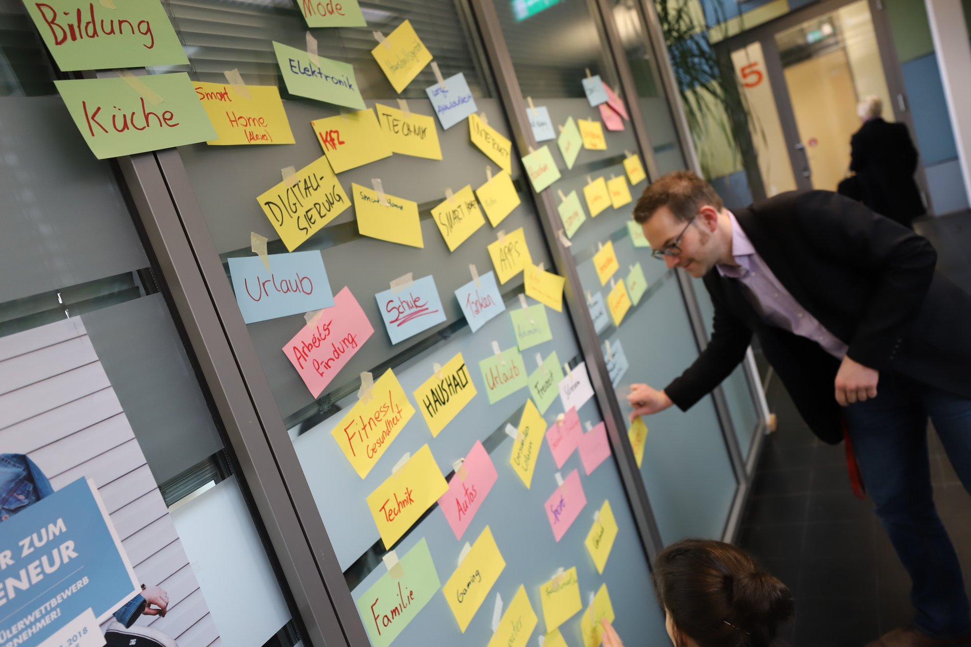 Dennis Tobias vom promotion school-Team vor einer Wand mit beschriebenen Klebezetteln.