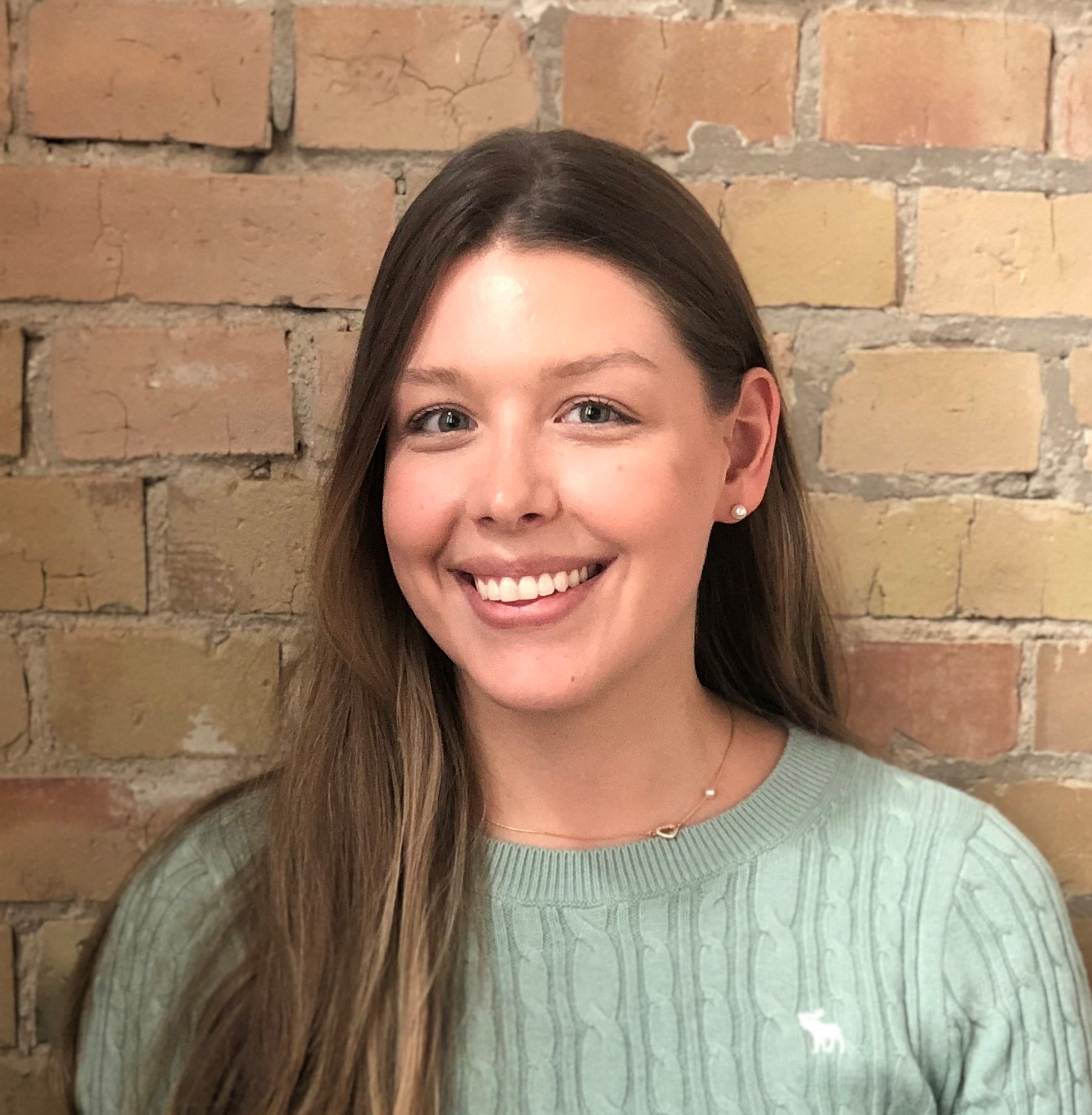 Das Portrait einer jungen Frau vor einer Steinmauer.