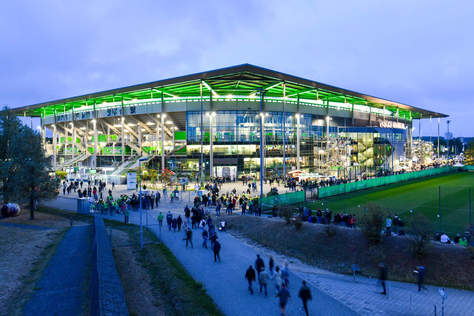 Man blickt am Abend auf die grün beleuchtete Volkswagen Arena