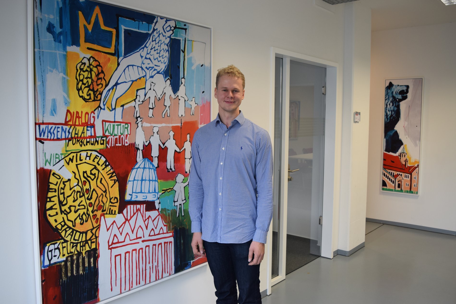 In den MENUX-Geschäftsräumen steht Engelmann neben einem Bild.