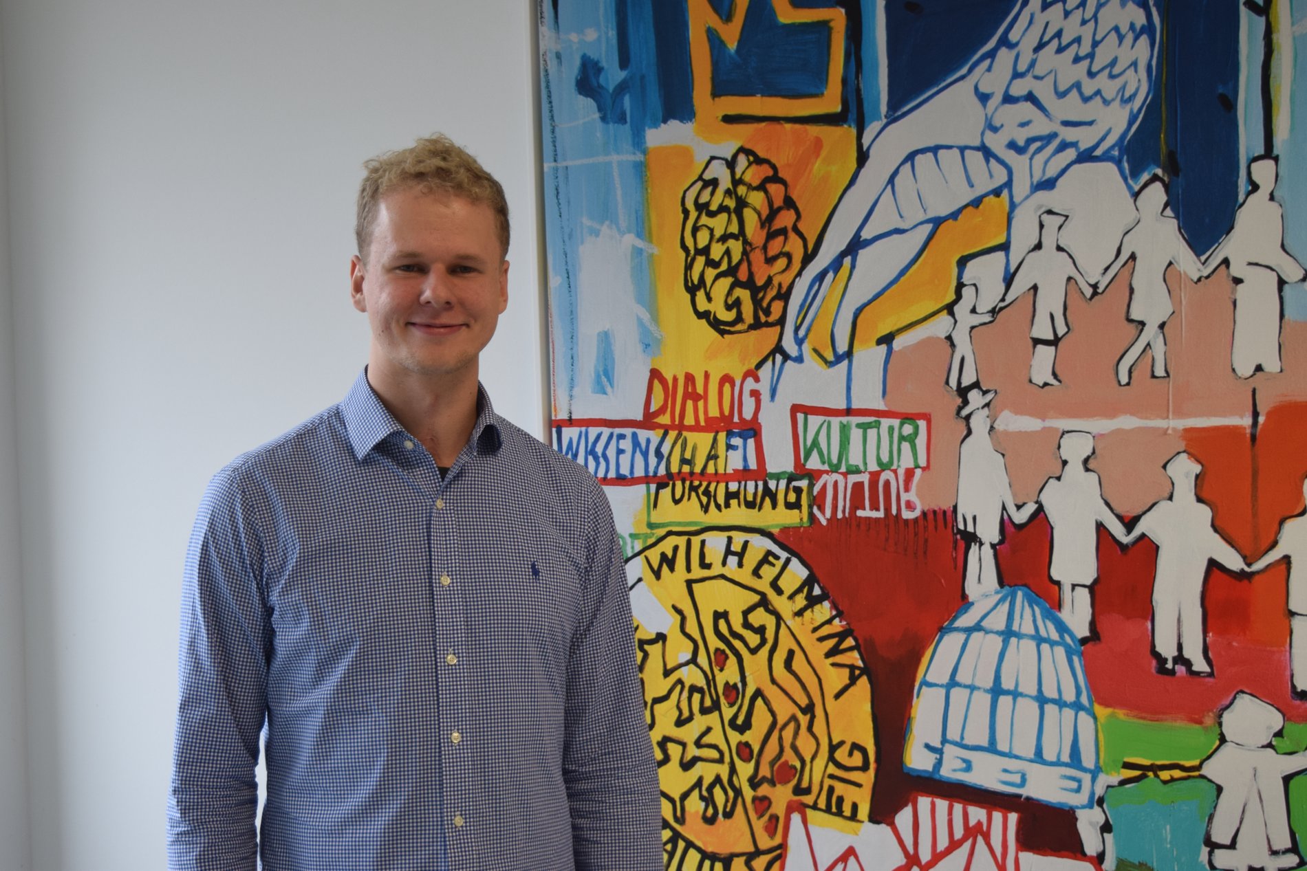 In seinen Geschäftsräumen steht Marcel Engelmann vor einem Bild.