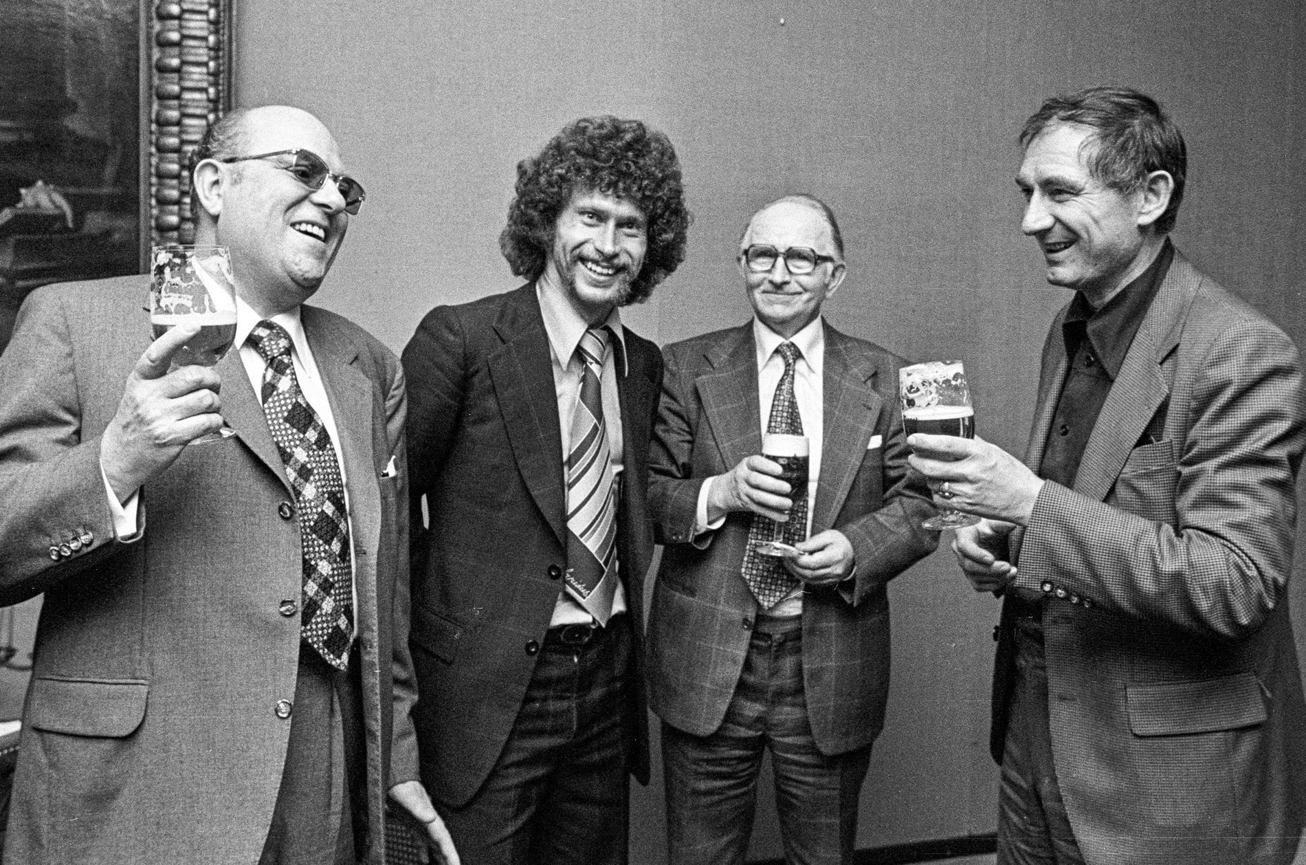 Vier Männer stoßen auf einem schwarz-weiß Bild mit Pilsbier an.