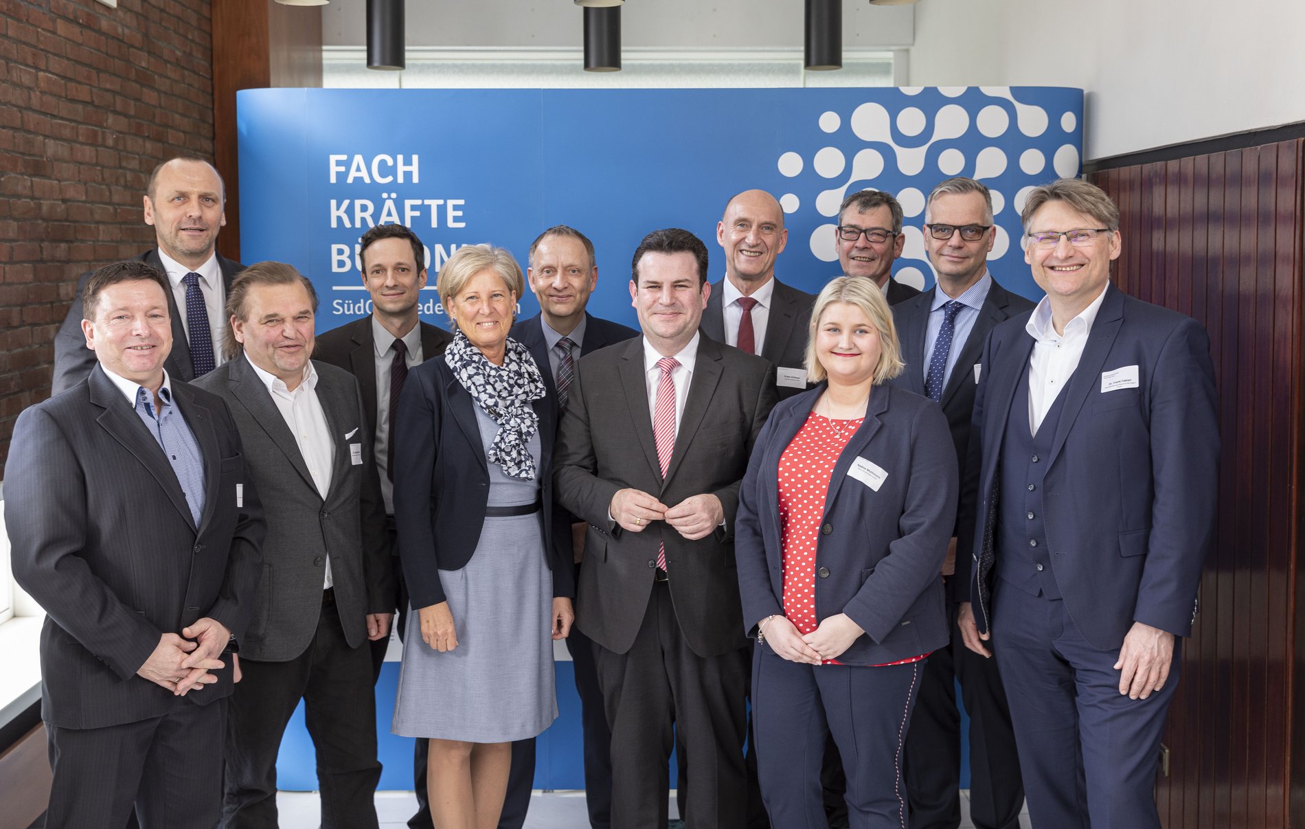 Firmenvertreter mit Arbeitsminister Hubertus Heil und ihren Partnern der Allianz für die Region vor einer Aufstellwand.