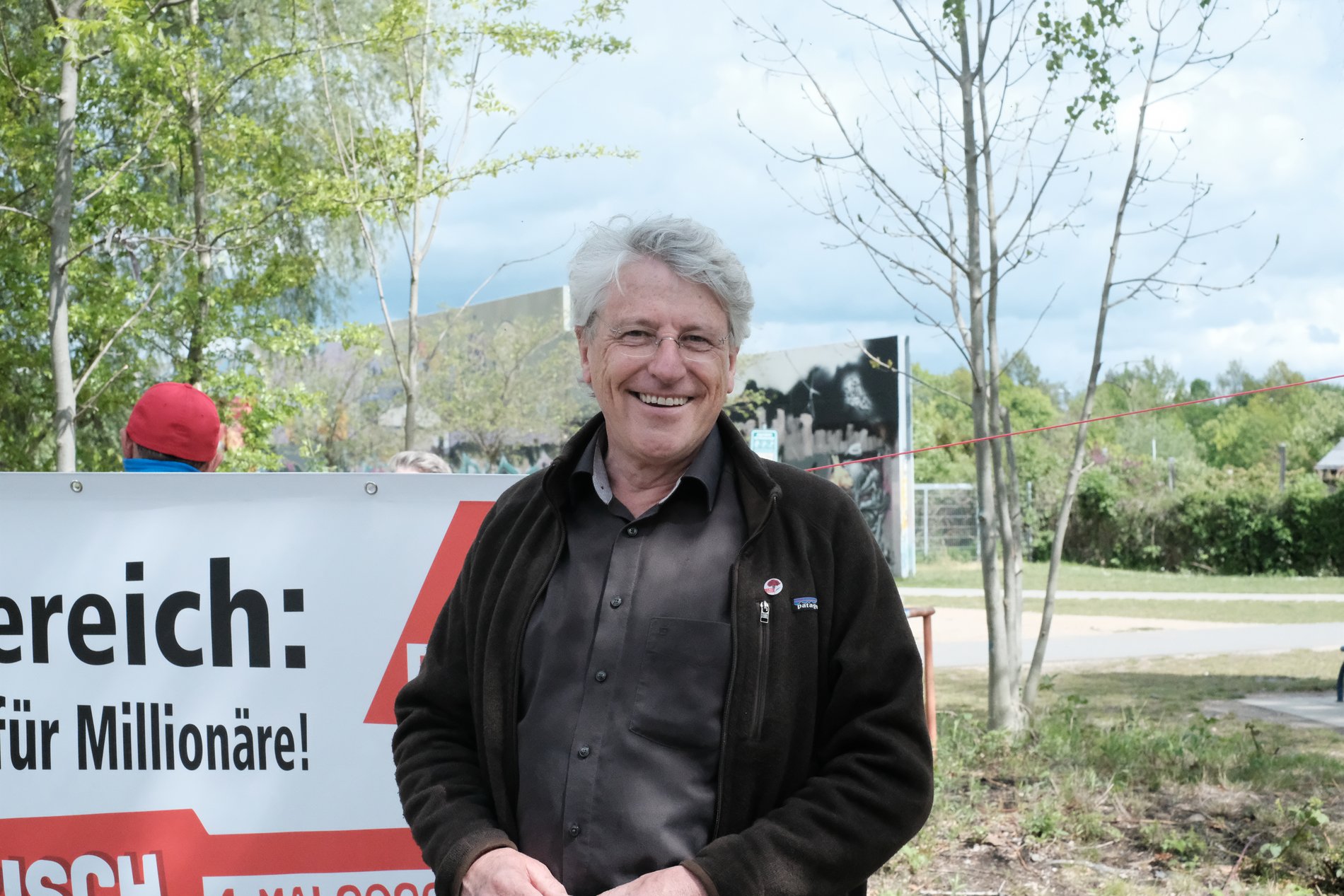 Ein Gewerkschaftler in dunkler Jacke vor einem Plakat in Braunschweig.