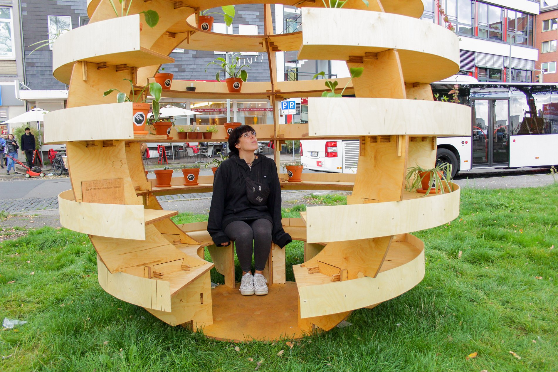 Eine junge Frau in einem Holz-Kokon auf dem Hagenmarkt.