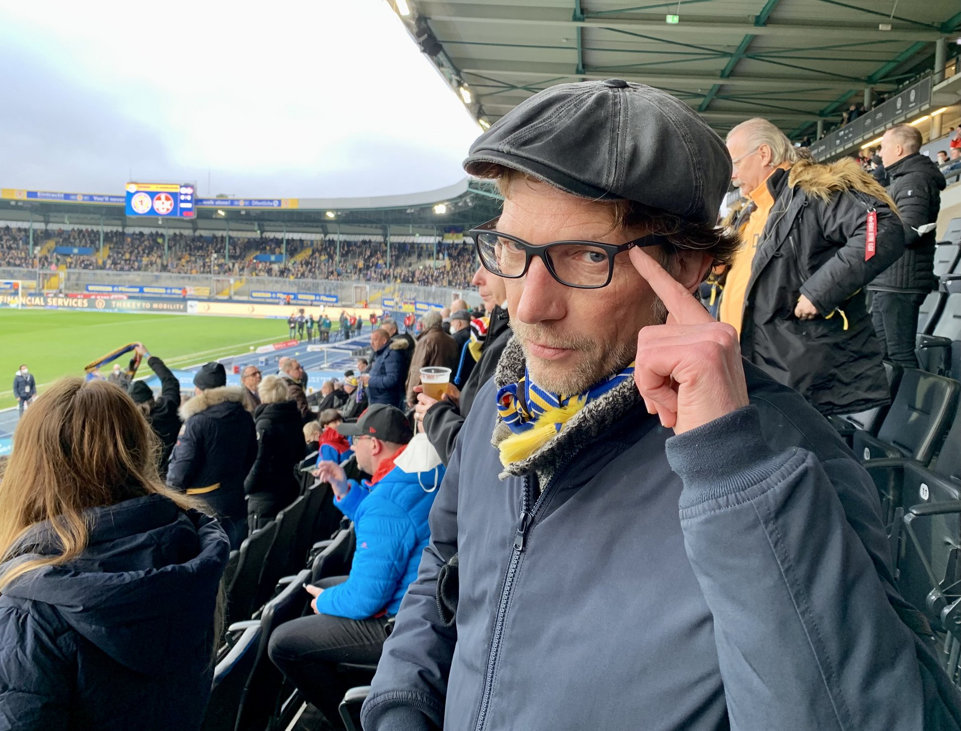 Ein Mann mit Mütze tippt sich an seine Brille.